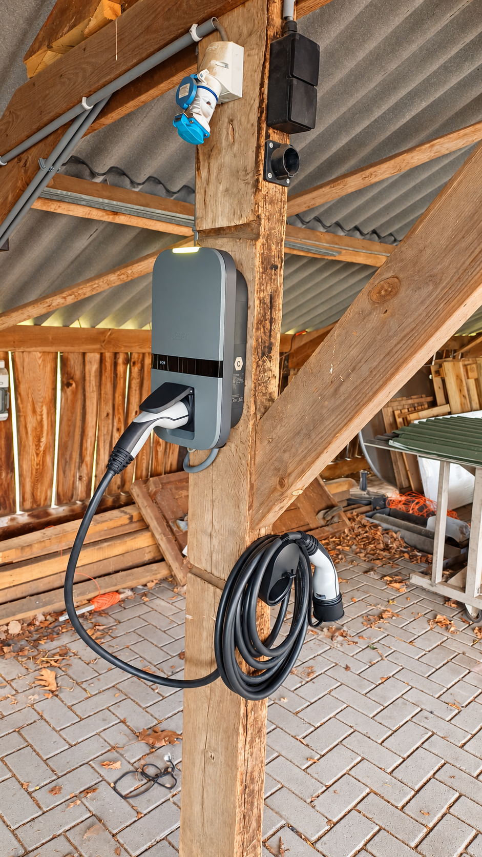 Peblar laadpaal met vaste laadkabel gemonteerd op een houten staander onder een overkapping