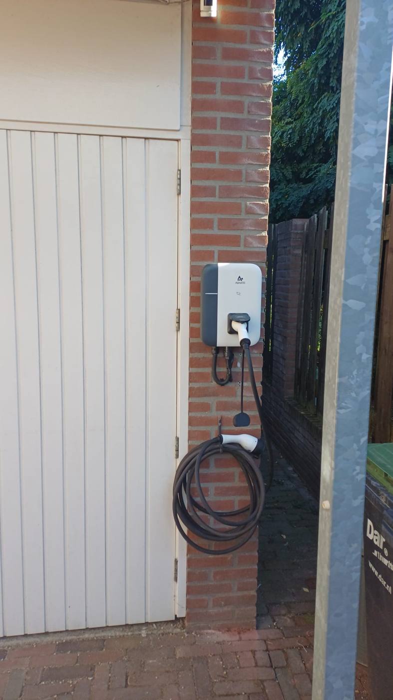 AlphaESS laadpaal met laadkabel aan een bakstenen muur naast de garage