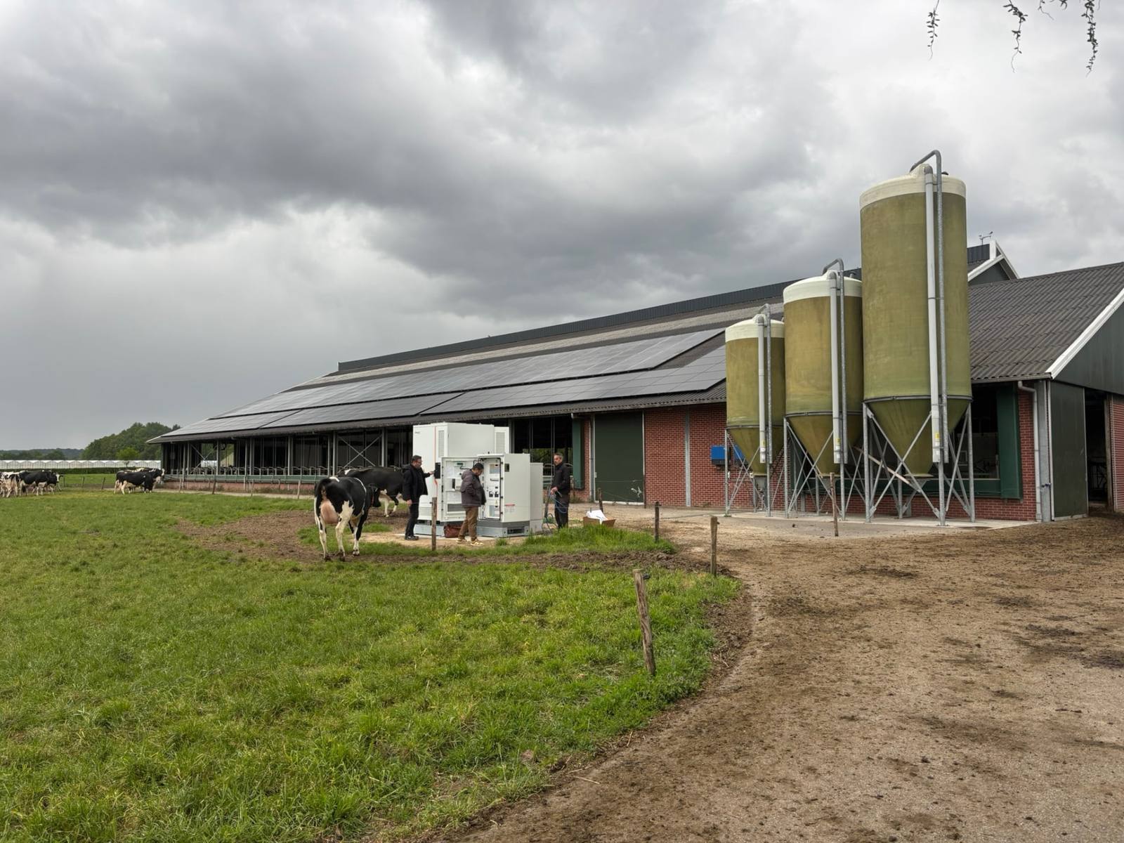 Batterijopslag naast silo's bij een agrarisch bedrijf met zonnepanelen op de stal
