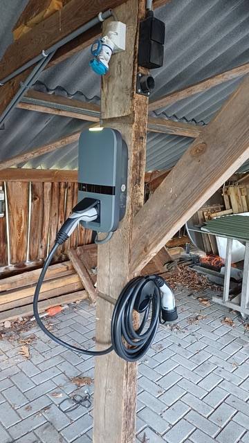 Laadpaal bij een woning onder een overkapping, met losse laadkabel voor het laden van een elektrische auto